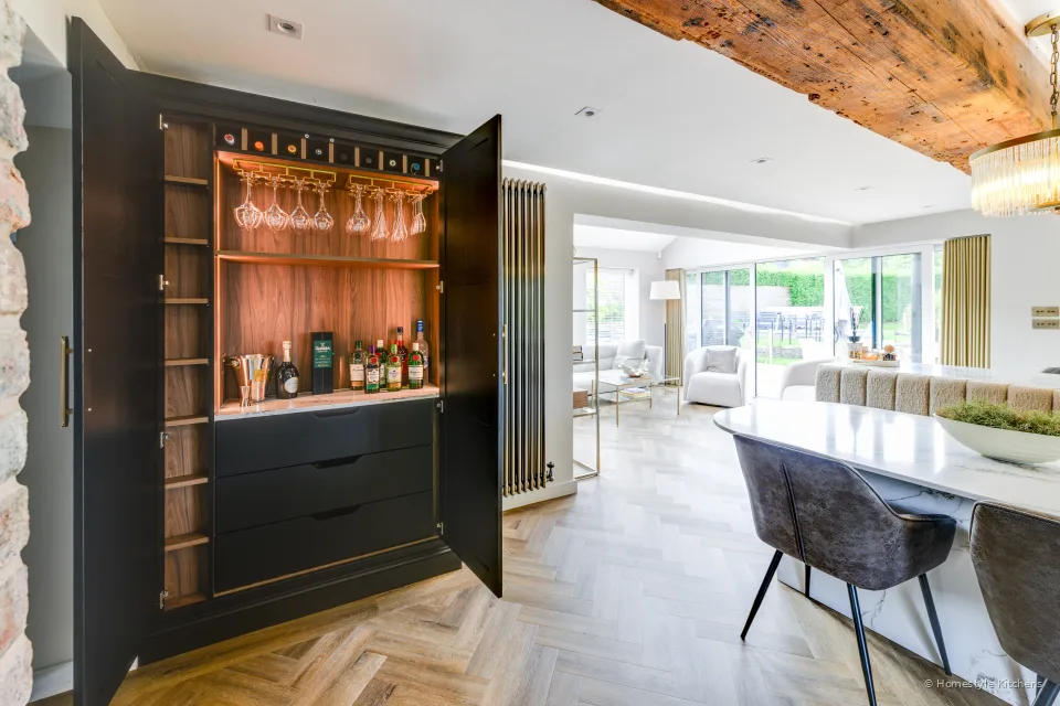 Charcoal Shaker bar with warm timber glassware display and white island beyond.