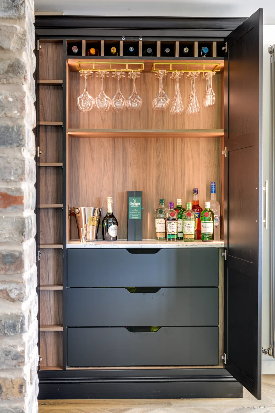 Close on the charcoal bar drawers and warm timber glassware shelves.