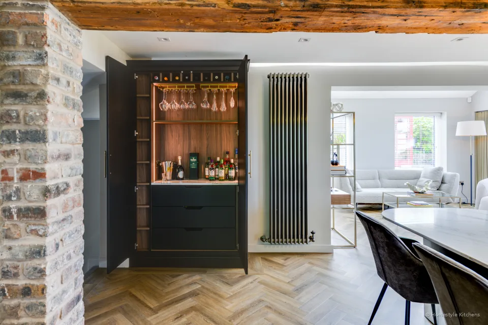 Charcoal bar cupboard open to a timber-lined lit display and white quartz top.