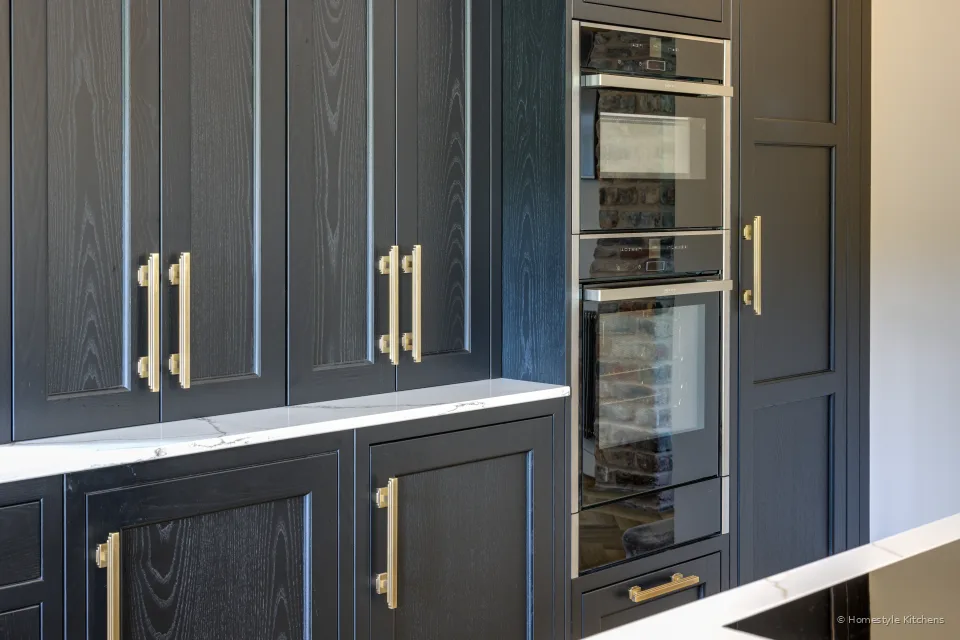 Charcoal talls with brass pulls, white quartz and a Caple wine cooler.
