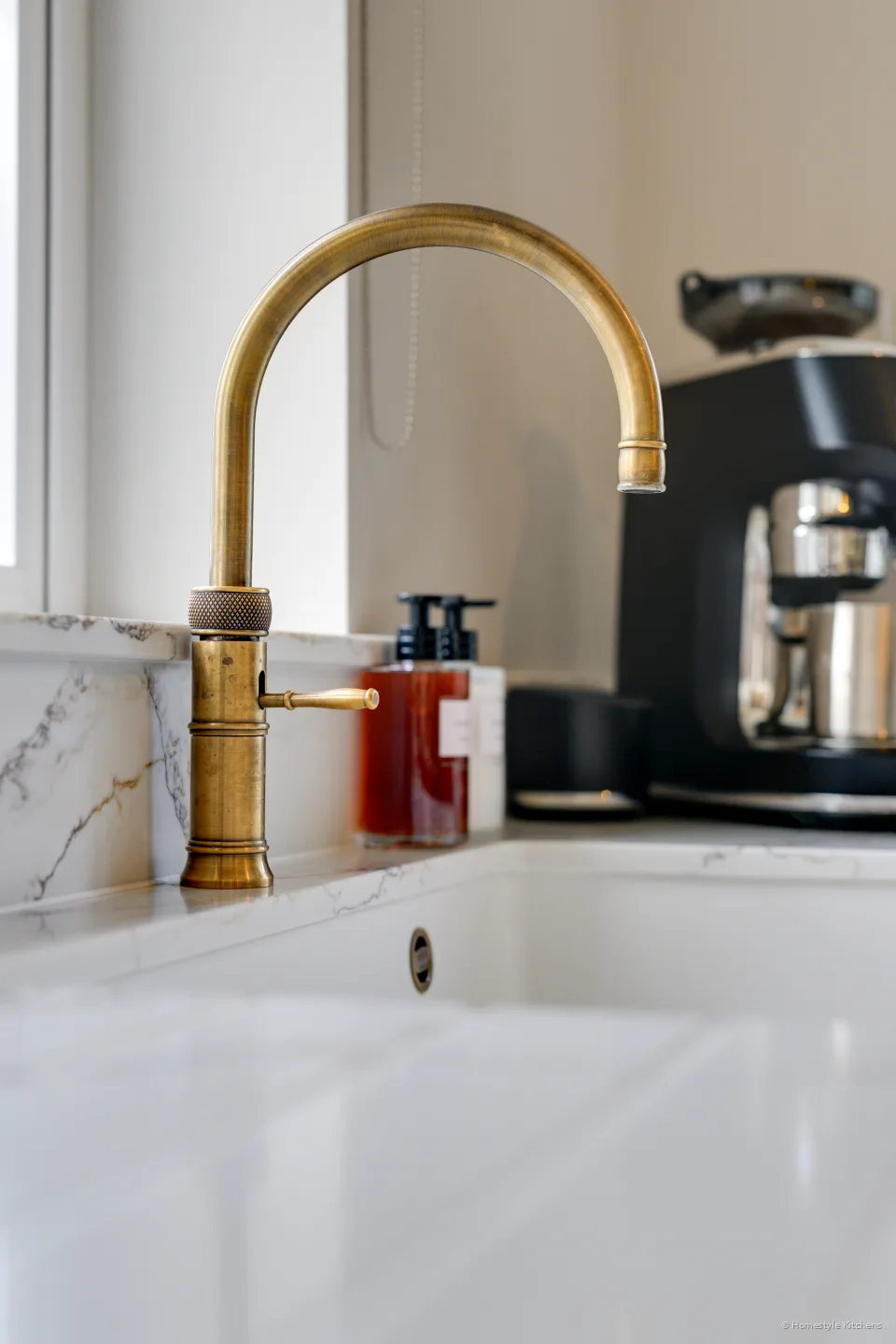 Quooker Fusion gooseneck in patinated brass over a white Caple sink.