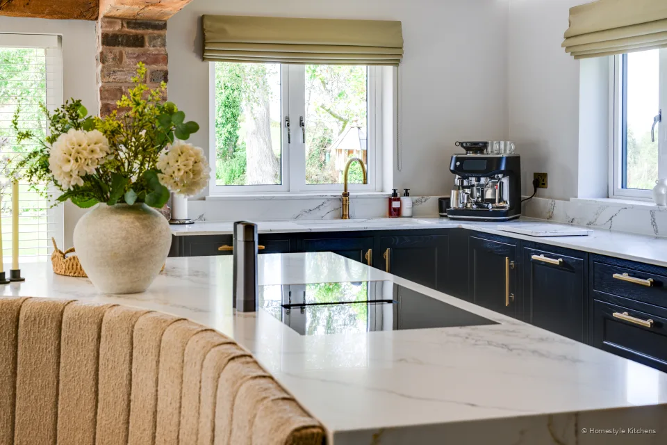 Charcoal base units, white quartz, brass tap and espresso machine under the window.
