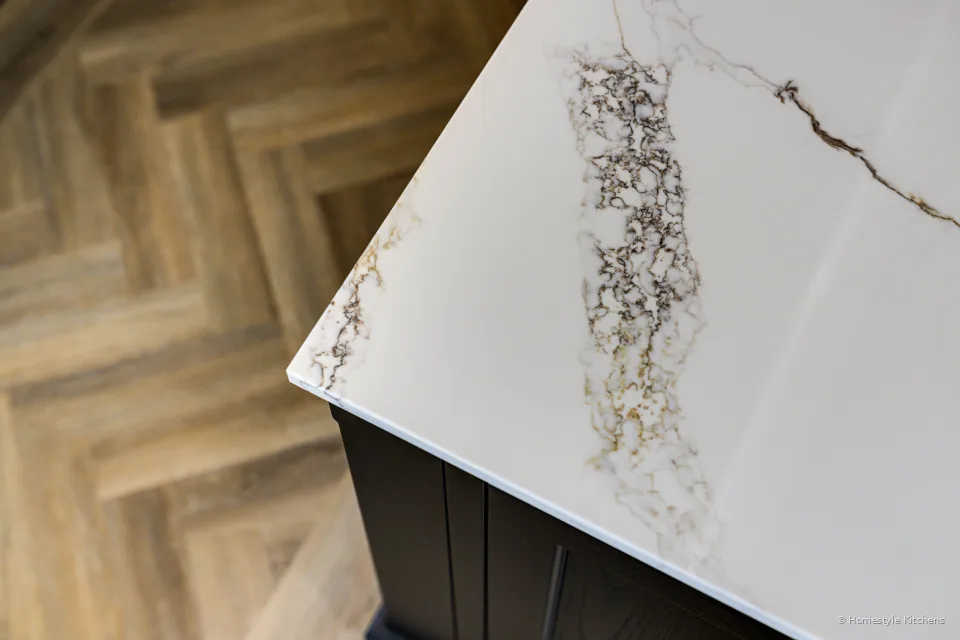 White quartz with strong grey and gold veining over charcoal cabinetry.