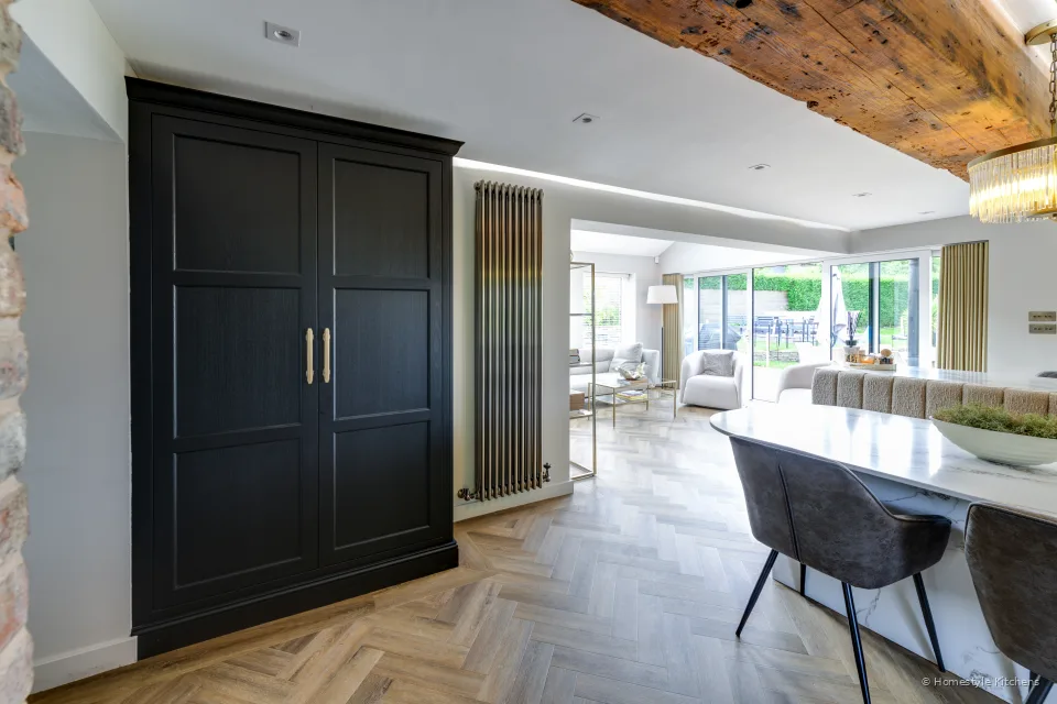 Tall charcoal pantry bank beside the dining, white quartz island and stools.