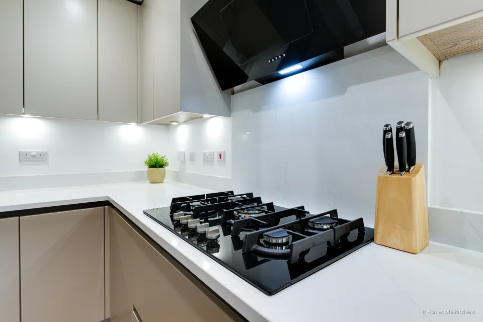 Black Neff gas hob and knife block on white quartz under pale grey units.