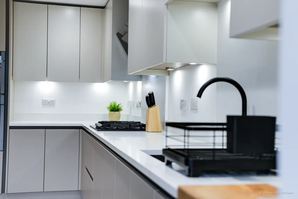 Angled overview: black sink and tap, gas hob, pale grey handleless run.