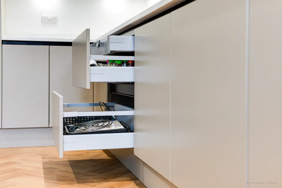 Open tall pantry with internal drawers beside pale grey cabinetry.