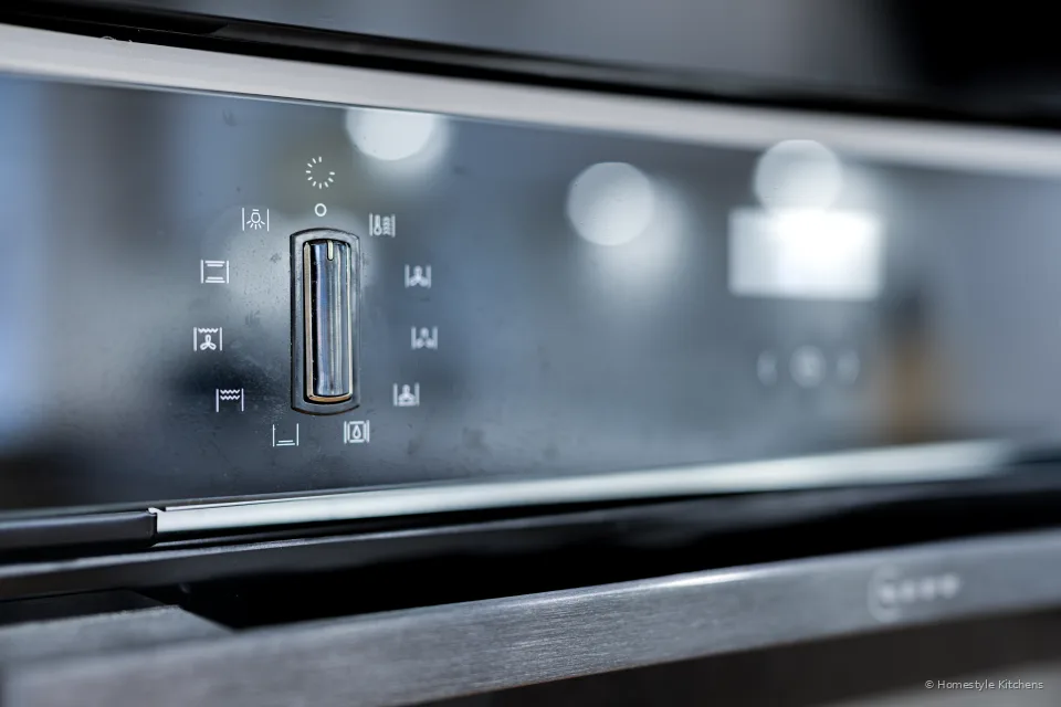 Dark hob and splashback with under-cabinet lighting, pale grey units.