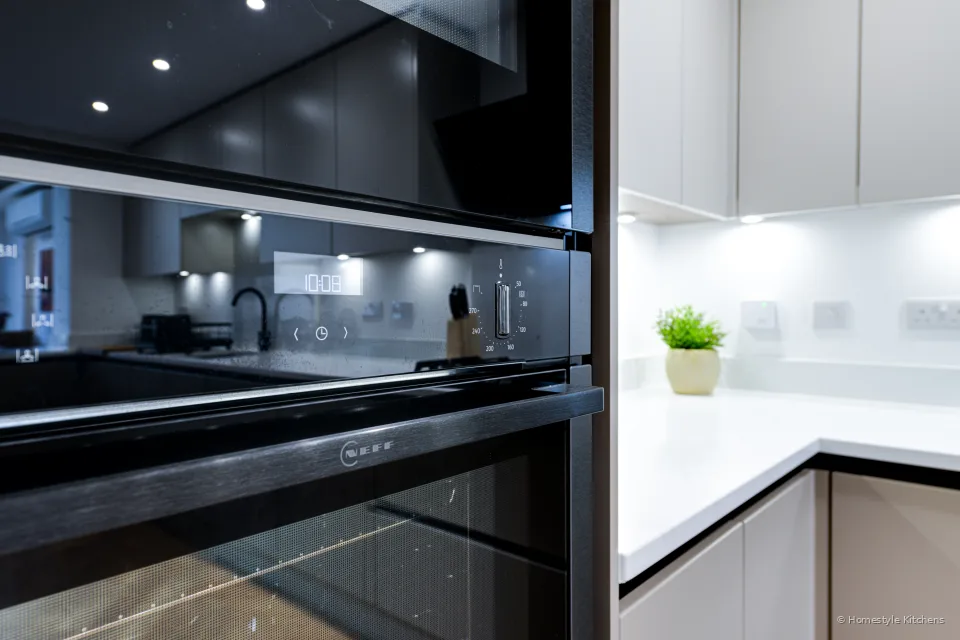 Black Neff oven stack and pale grey cabinets on a pale worktop.