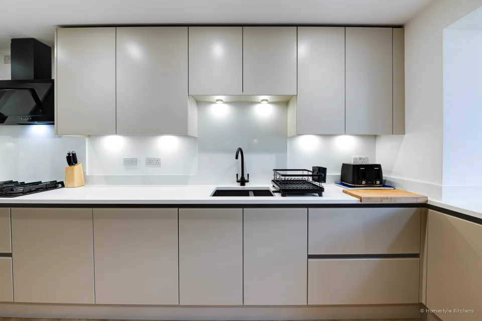 Straight-on pale grey run with black hob, angled extractor and sink area.