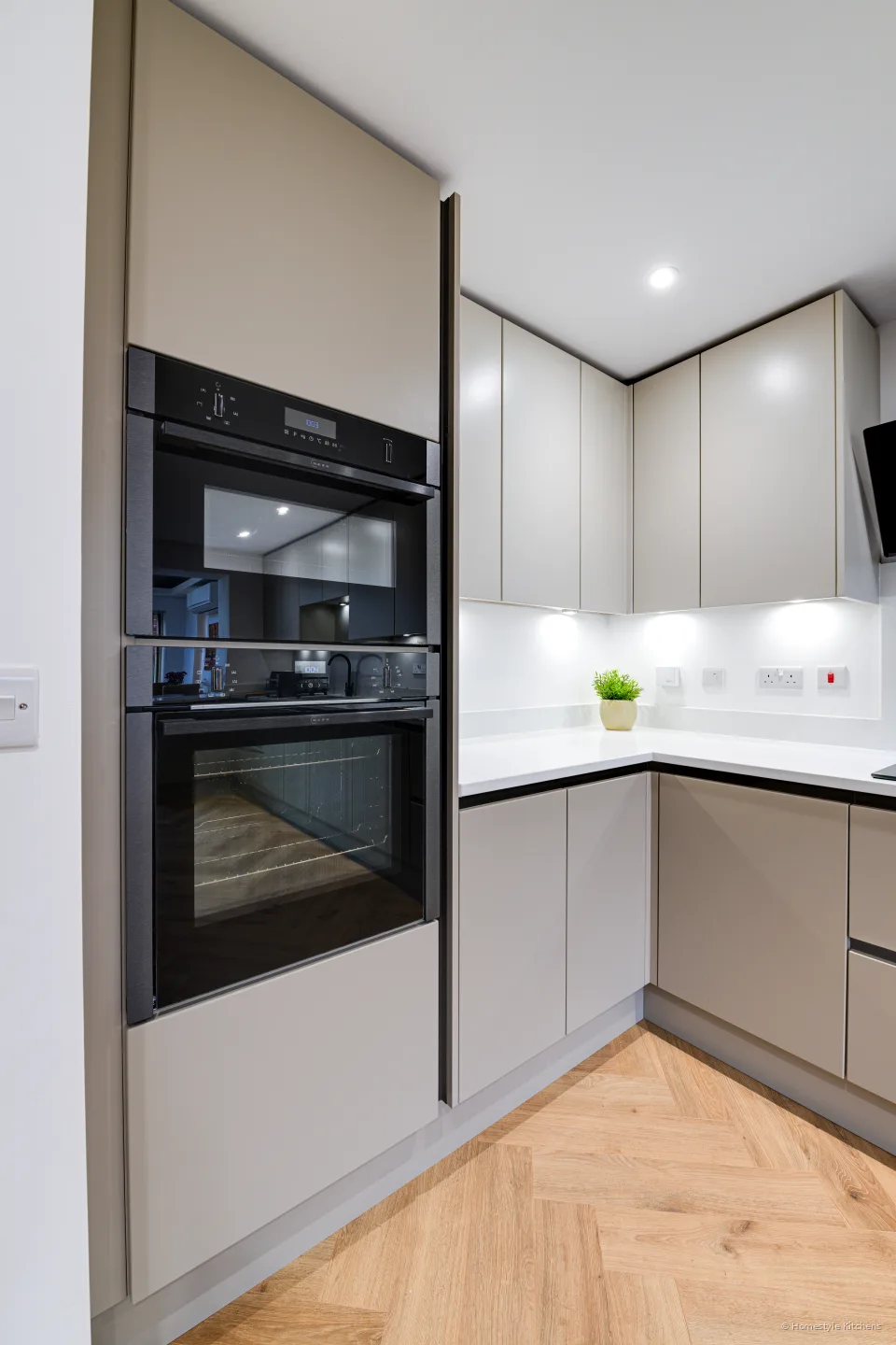 Tall integrated black Neff ovens beside pale grey handleless cabinetry.
