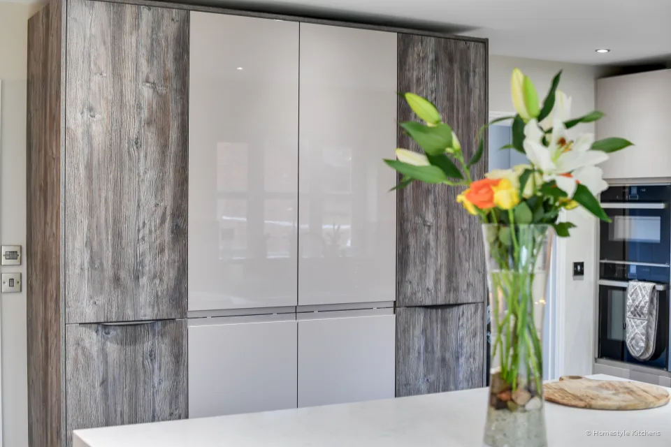 Tall kitchen cabinets with timber effect and plain doors and flower vase