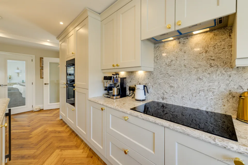 Cream painted hob run with ovens beyond and a doorway to the hall.