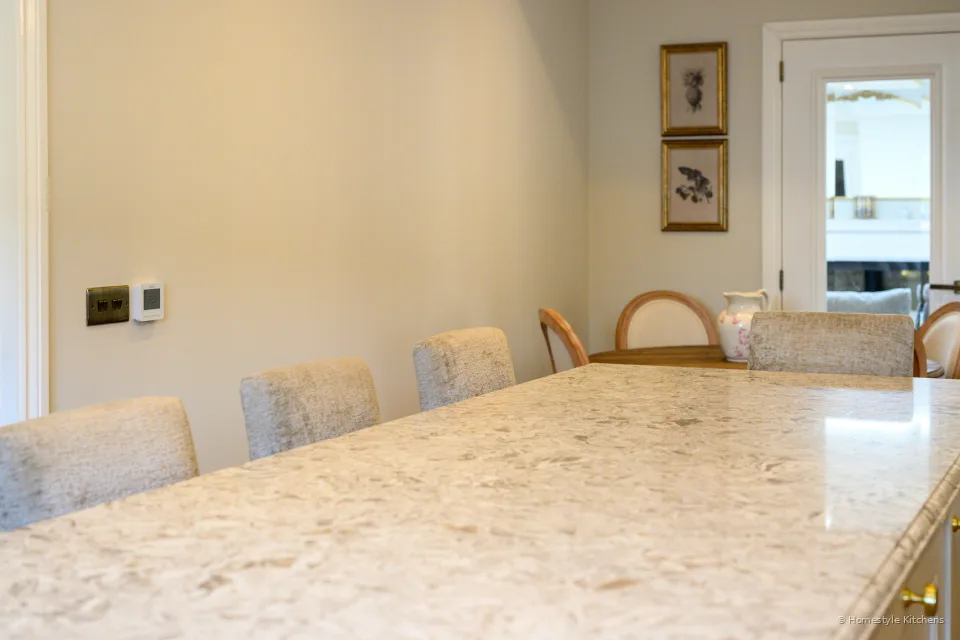 Marbled quartz island looking toward a dining doorway, cream cabinets to the side.