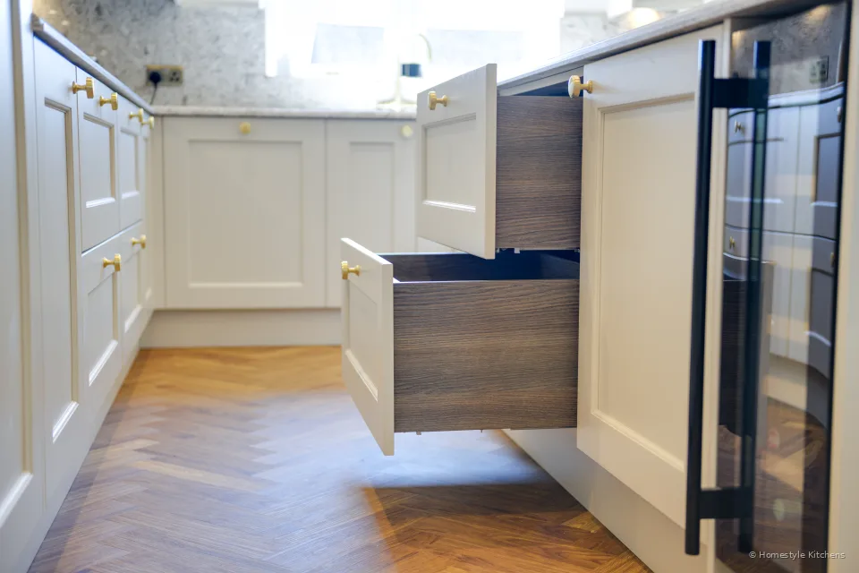 Open drawer in a cream island beside a black wine cooler.