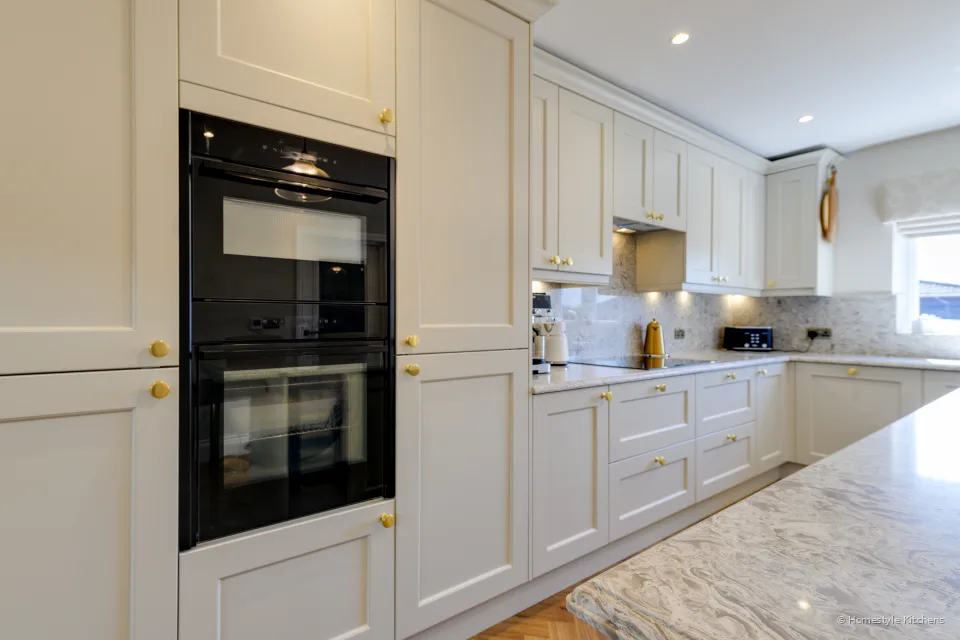Black double oven in a cream tall housing, island worktop in the foreground.