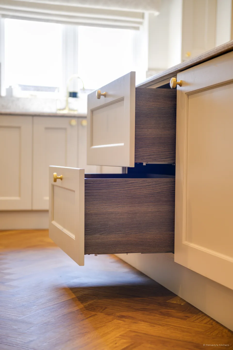 Open cream painted drawers with dark interiors, herringbone floor.