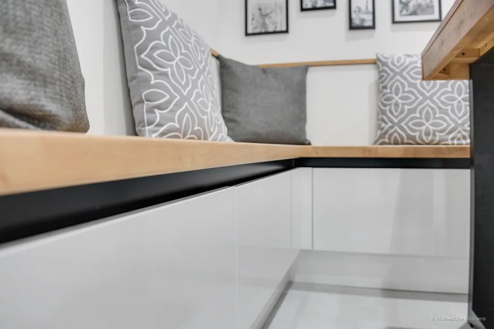 Built-in oak banquette on white gloss units with a black handleless rail and grey cushions.