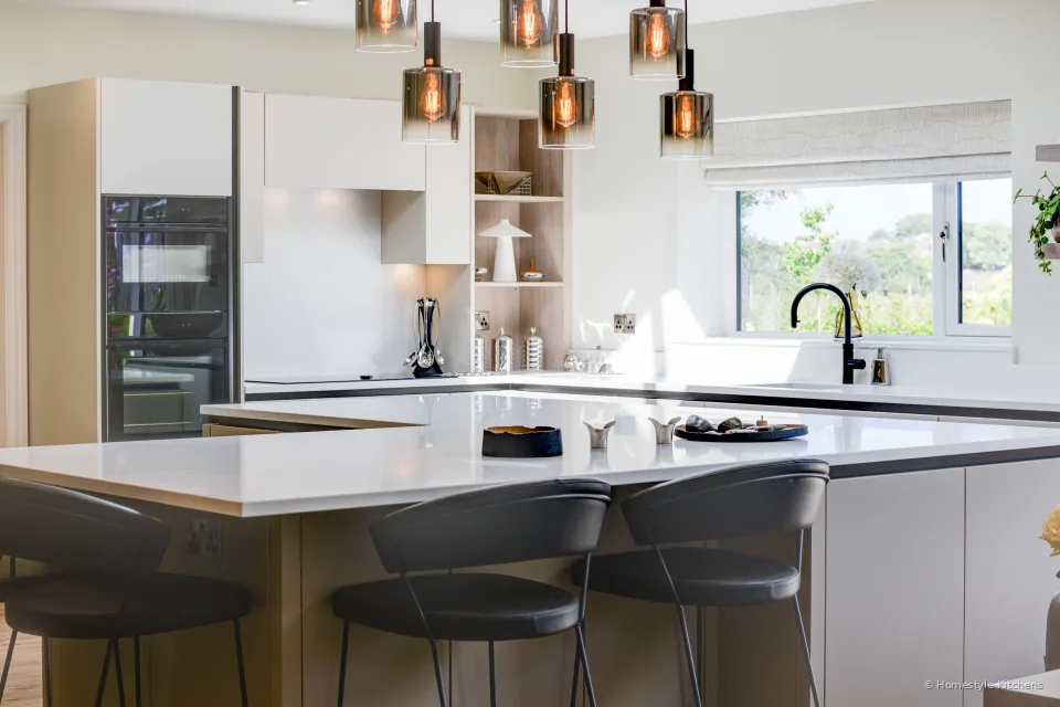Breakfast bar with dark stools, black hob and copper pendants over the island.