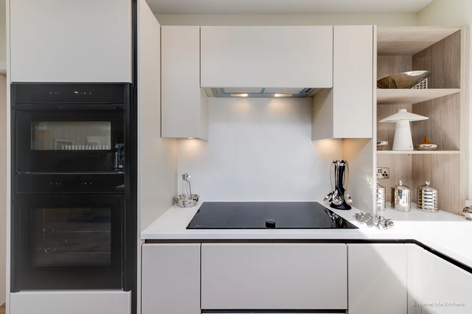 Black Neff ovens beside cream handleless units, induction hob in white quartz.