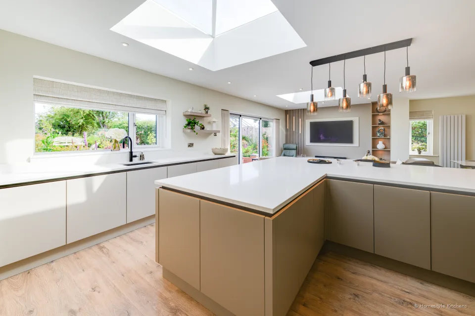 L-shaped cream run with wall cabinets, white worktop and a garden window.