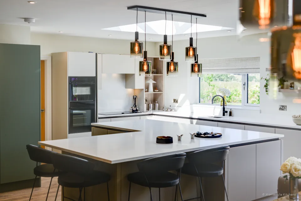 Island with copper pendants, oven bank behind.