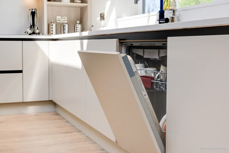 Integrated dishwasher open in a cream handleless run.