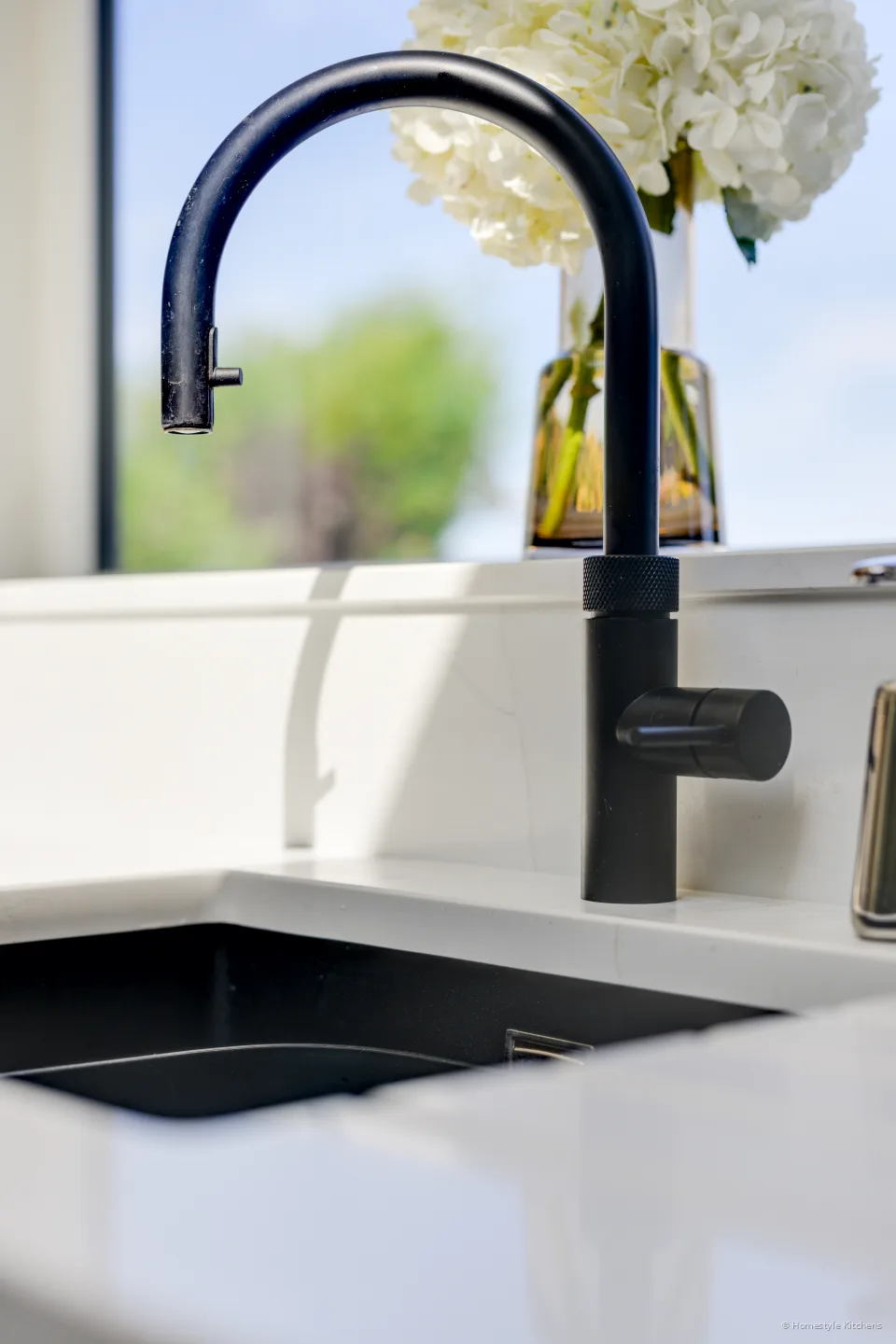 Black Quooker Flex pull-out over a black Caple undermount in white quartz.