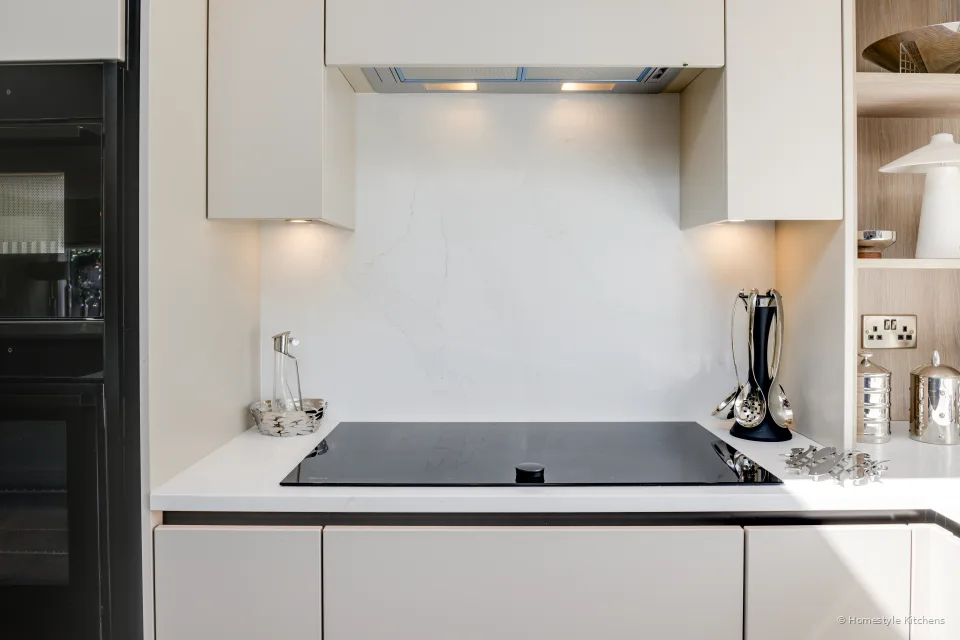 Black induction hob in white quartz, ovens to the left.