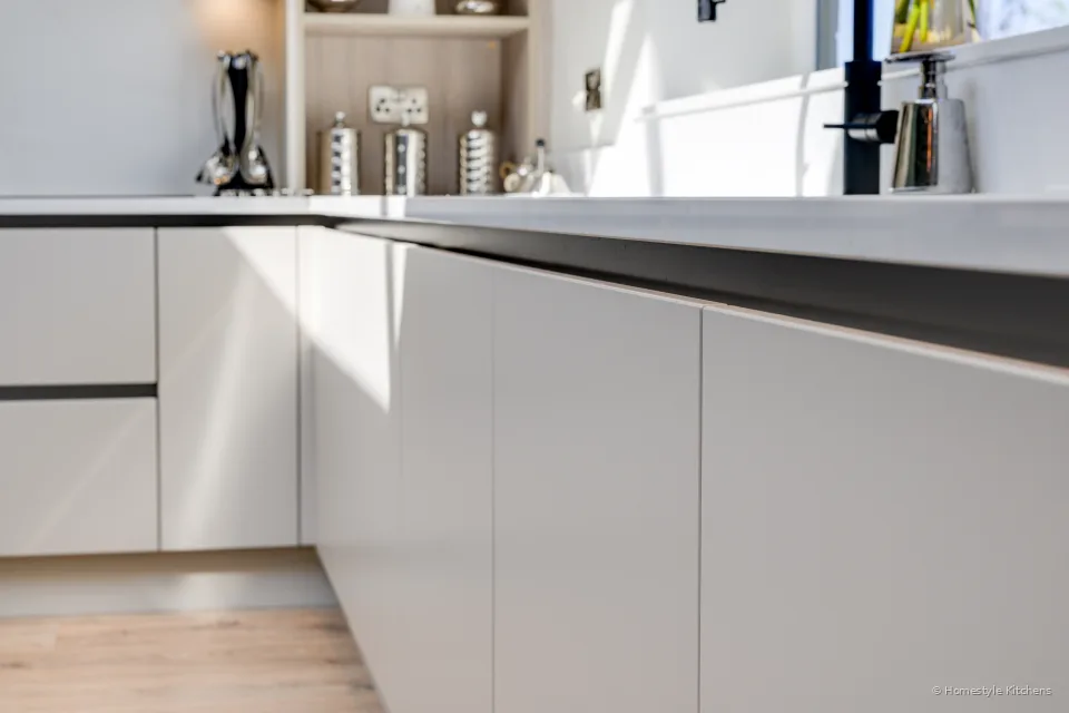 Cream base units and worktop, handleless rails.