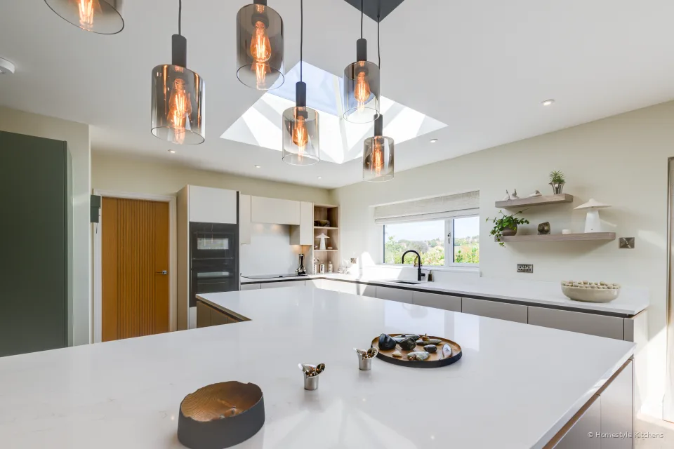Island with a bowl, copper pendants, open shelf on the rear wall.