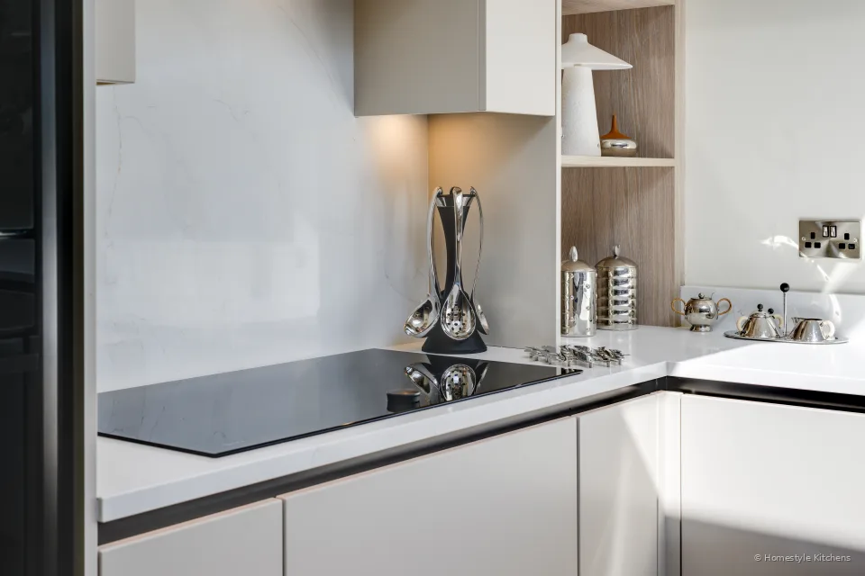 Black induction hob close in, quartz splashback and oak shelf.