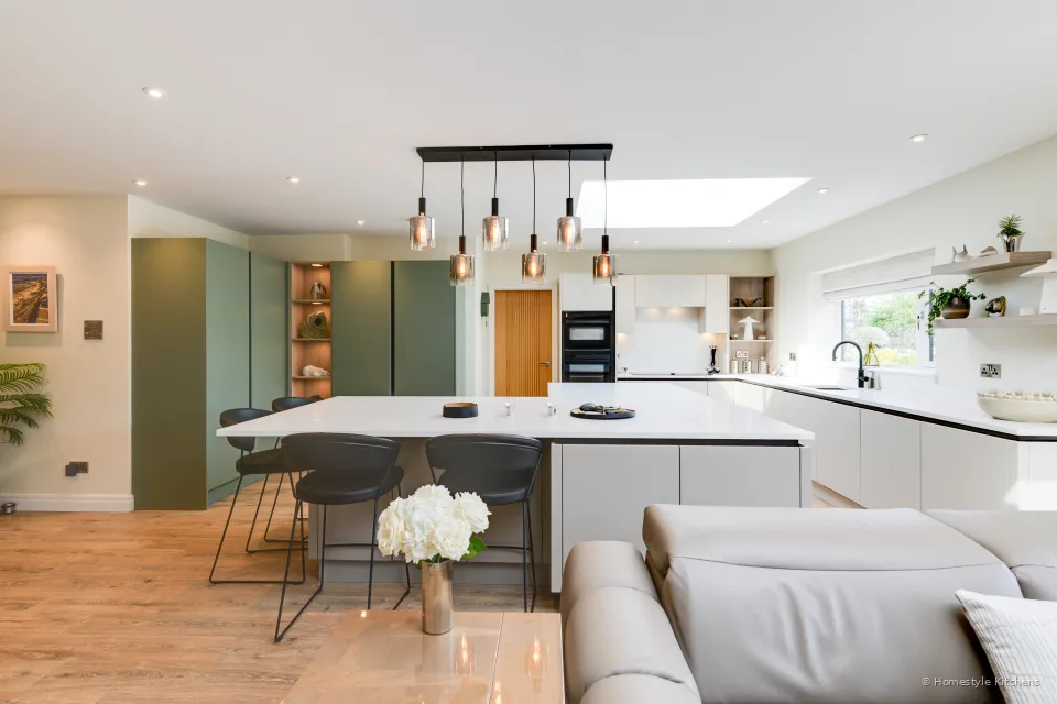 Handleless kitchen island in stone taupe, reed green talls, white quartz and copper pendants.