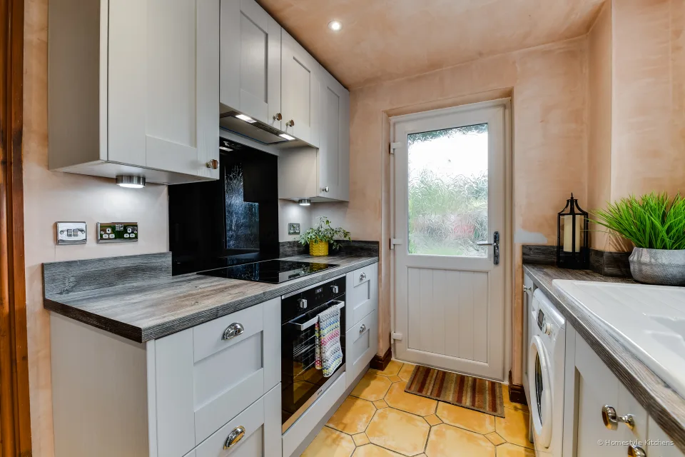 Light grey shaker kitchen with cup handles dark worktop black oven and washing machine