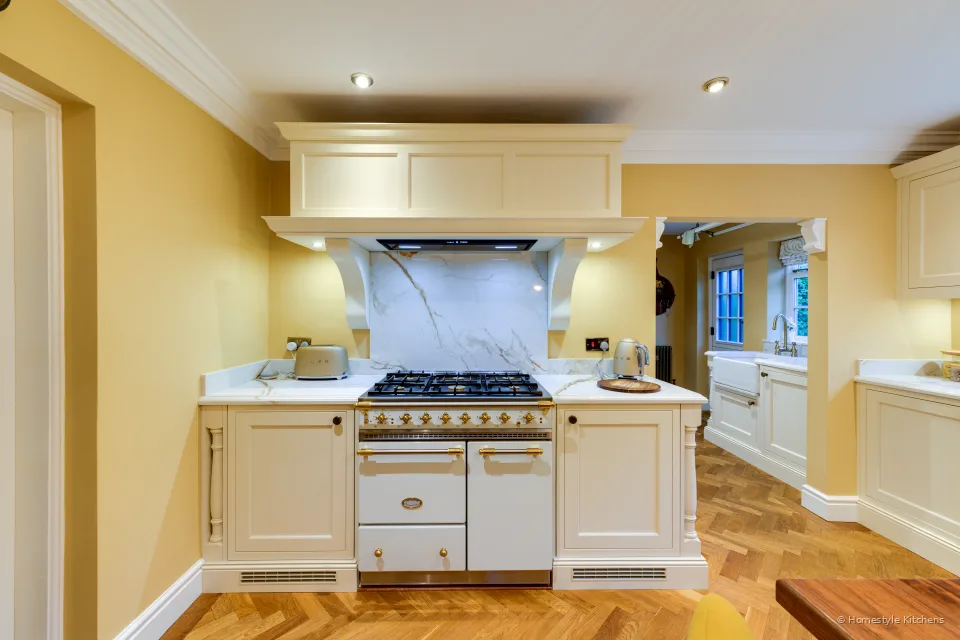 Cream painted canopy and cabinets around a range cooker, Calacatta Gold quartz splashback and worktops.