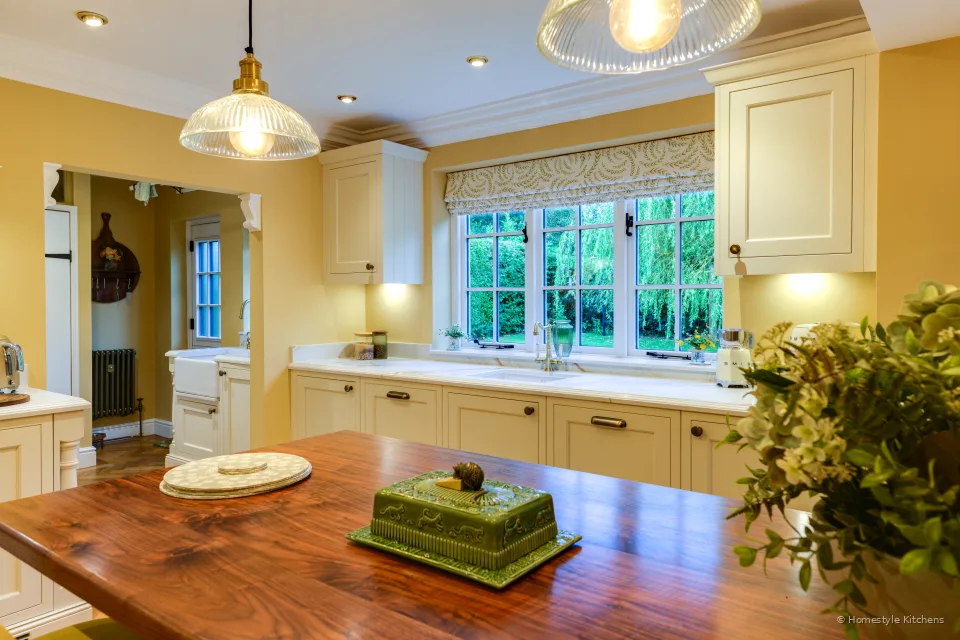 Green ceramic dish on an oak island top, cream painted window run and Calacatta Gold worktop beyond.