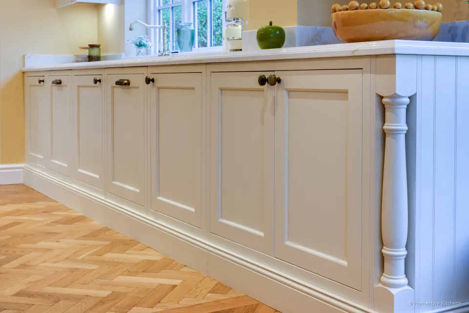 Long run of cream painted in-frame cabinets with brass handles, Calacatta Gold worktop and herringbone floor.