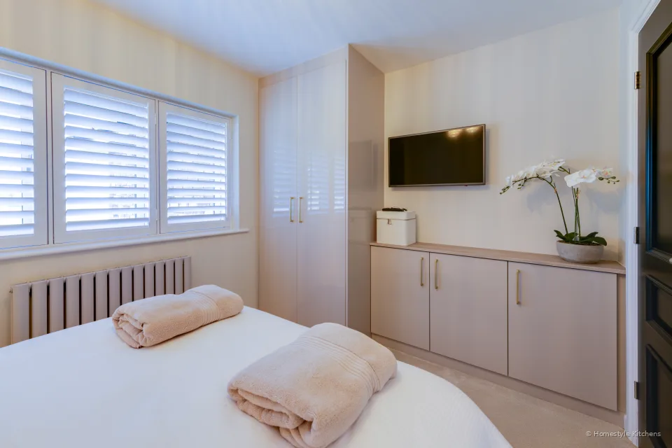 Bed with pale fitted cabinetry and a wall-mounted TV.
