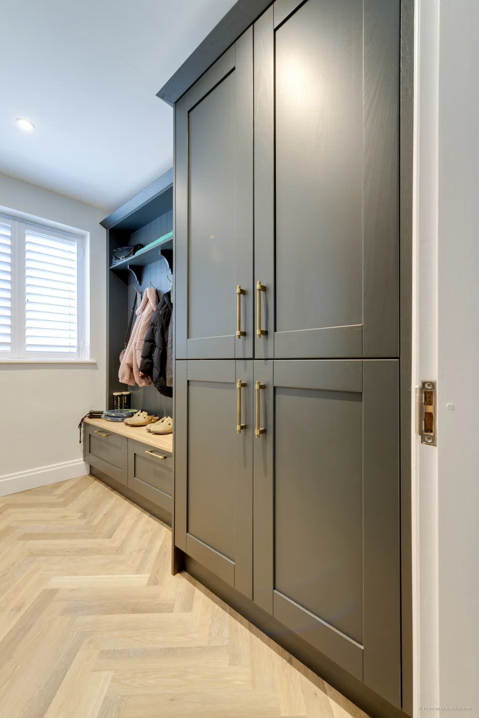 Grey-blue shaker tall units, oak bench and brass handles.