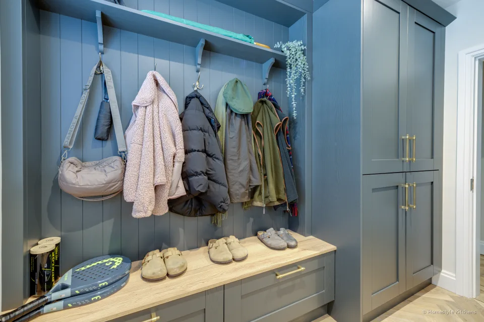 Boot room hooks with coats, oak bench and drawers below.