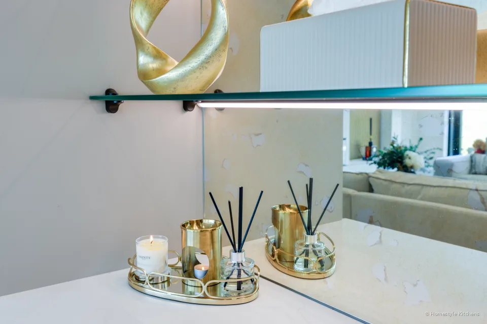 Gold tray and diffusers on a white quartz dressing top, mirrored wall behind.