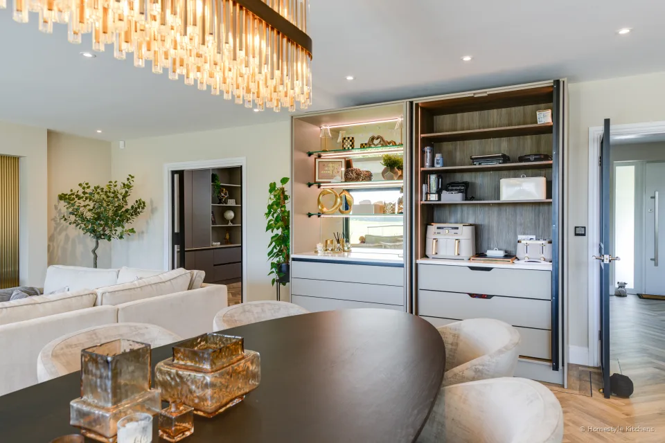 Dark oak-lined larder open in pale handleless units, quartz worktop.