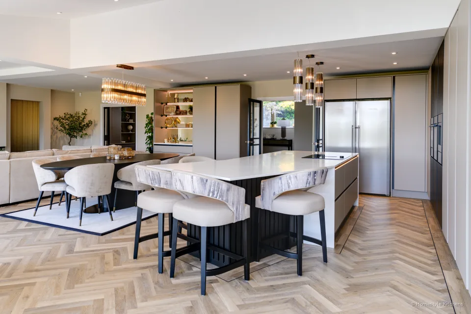 Long pale grey island with white quartz worktop, handleless slab doors.