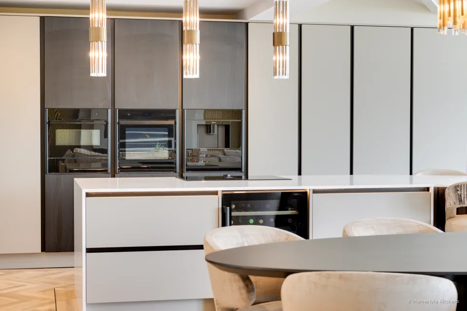 Kitchen peninsula with a matt black tap under a window, white quartz worktop.