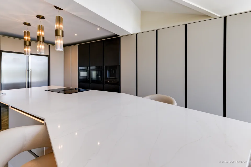 White quartz island top close in, brass pendants above.