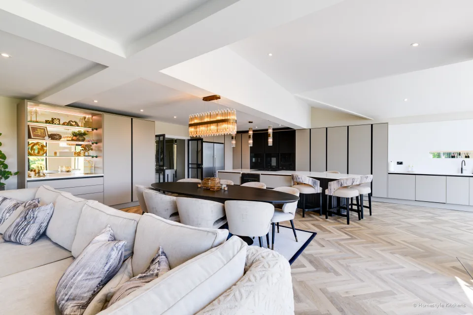 Dark tall kitchen housing and brass pendants over a pale grey island.