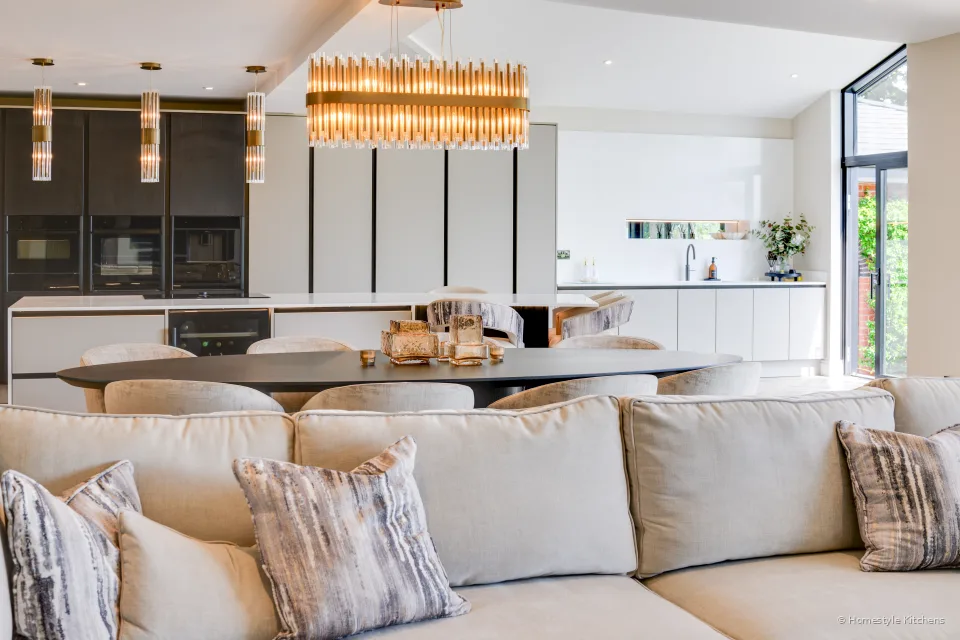 Island wine fridge and lit shelving in a pale grey kitchen.