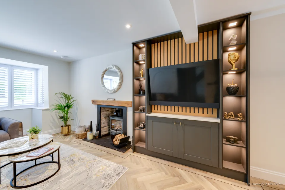 Media wall with slatted oak, lit shelving and a log burner.