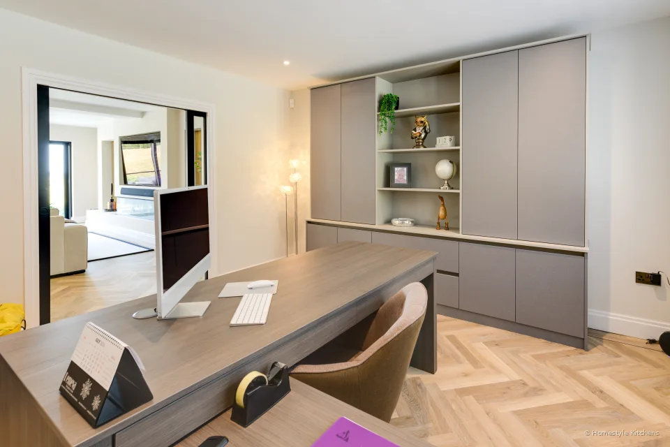 Dark timber desk with taupe handleless units behind.
