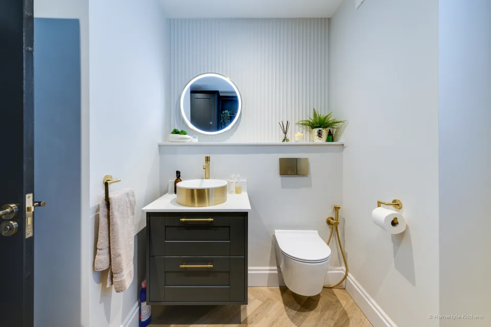 Dark green cloakroom vanity, brass basin and tap, wall-hung WC.